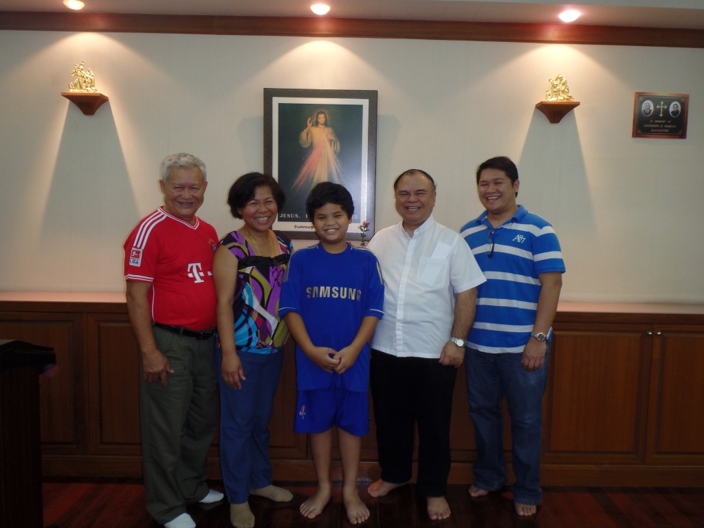 The author, Maria Sherr with her immediately family, Fr. John Tamayo, SDB and Arjames Balgoa (far right).  Photo taken inside the Salesians of Don Bosco chapel in Bangkok, Thailand with the photo of the Divine Mercy in the background. 